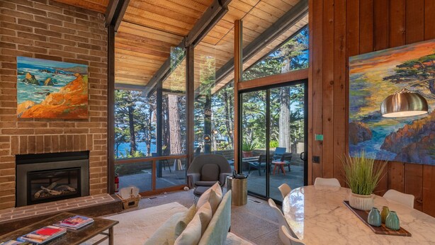 A modern living room with a fireplace, large windows, and a dining area. - Pebble Beach perfection. Peaceful, Ocean view property to rest, golf, reset. (Del Monte Forest)
