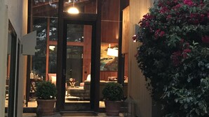 A modern building entrance with a wooden facade, large windows, and a well-lit interior visible through the glass doors. - Pebble Beach perfection. Peaceful, Ocean view property to rest, golf, reset. (Del Monte Forest)