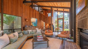 A spacious living room with a wooden interior, a large sofa, a coffee table, and a fireplace. - Pebble Beach perfection. Peaceful, Ocean view property to rest, golf, reset. (Del Monte Forest)