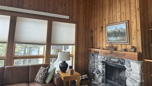 Una stanza accogliente con pareti in legno, un camino in pietra, un quadro incorniciato e un divano in pelle.