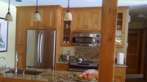 Cucina con mobili in legno, elettrodomestici in acciaio inossidabile e un piano di lavoro in granito.