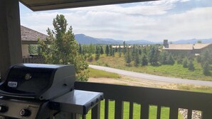 Un balcone con una griglia Weber Spirit, con vista su una strada, alberi e montagne lontane.