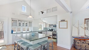 Une cuisine spacieuse avec un îlot central, des tabourets de bar et une maquette de bateau de style rustique.