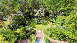 A lush garden with a central fountain, manicured lawns, and a variety of trees and shrubs. - True Southern Historic Charm by the Battery with Enchanting Charleston Gardens (Charleston)