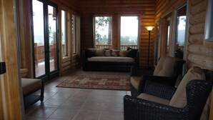 A log cabin interior with a sofa, two wicker chairs, a rug, and a wooden floor. - Premium Mountain Retreat On Over 2 Acres With Sweeping Views-hot Tub/Pool Table (Ruidoso)