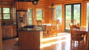 A wooden cabin interior with a kitchen, dining area, and large windows. - Premium Mountain Retreat On Over 2 Acres With Sweeping Views-hot Tub/Pool Table (Ruidoso)