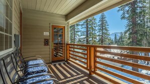 A wooden deck with a railing, a door, and a bench area with patterned cushions. - Refined Rustic Retreat | Walk to Canyon Lodge, Hot Tub, Sauna & Garage (Mammoth Lakes)