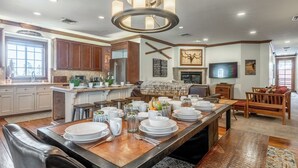 A spacious kitchen with a large island, wooden cabinets, and a modern chandelier. - Refined Rustic Retreat | Walk to Canyon Lodge, Hot Tub, Sauna & Garage (Mammoth Lakes)