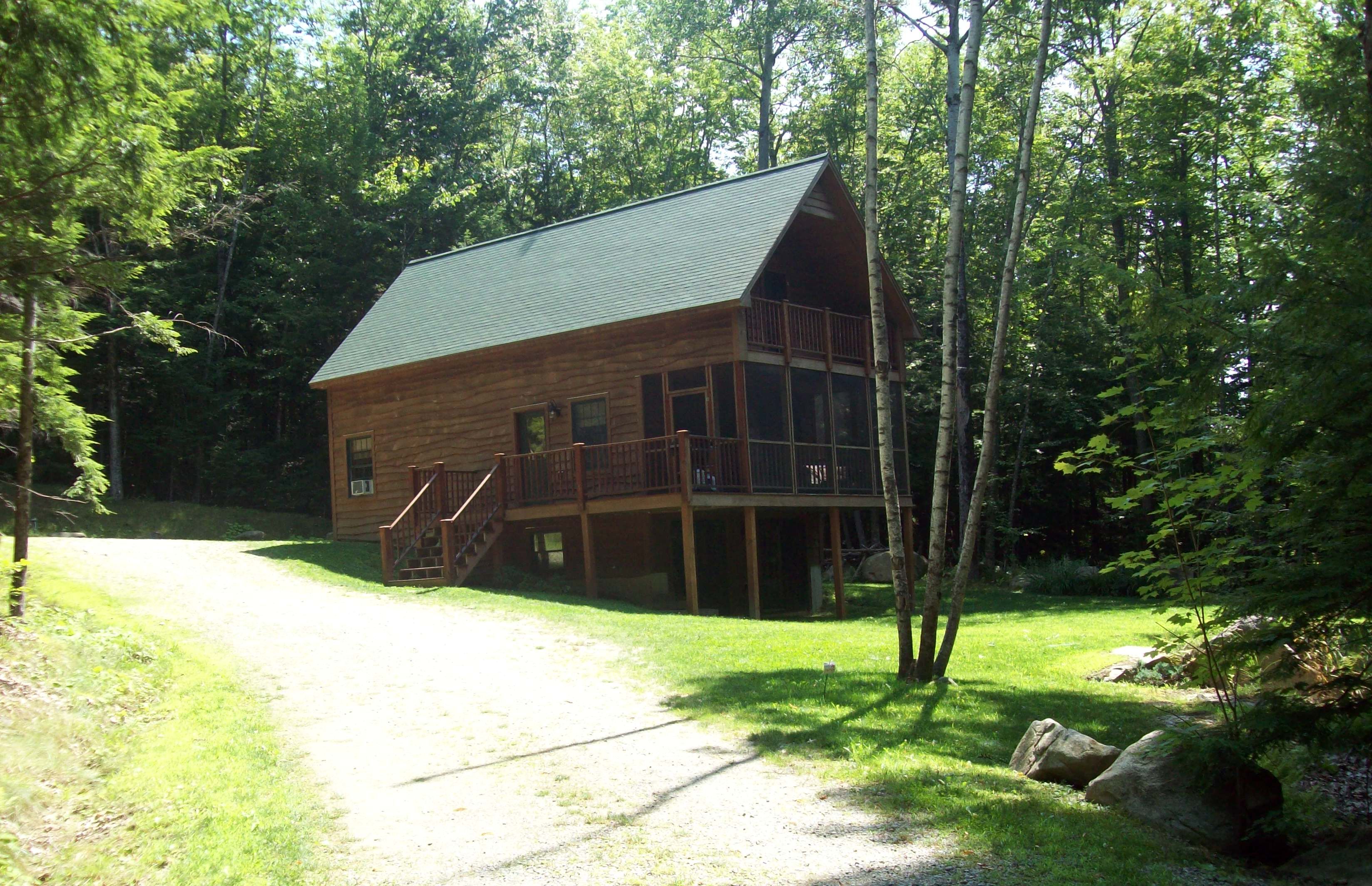 Une cabane en bois avec un toit en métal, une terrasse et un escalier menant à l’étage principal.
