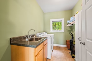 A compact kitchen with a sink, stove, and window overlooking greenery.