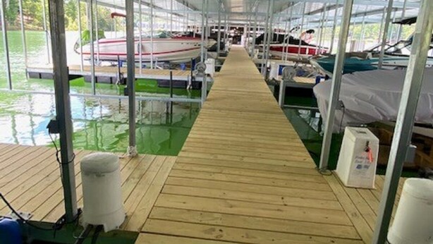 A covered boat dock with a wooden walkway leading to boats.