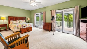A bedroom with a bed, a desk, a chair, a dresser, a telescope, and a balcony with a TV.