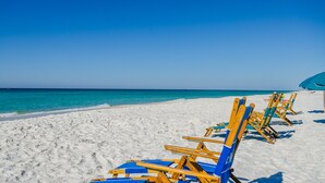 Ein Strand mit Reihen aus Holzliegen und Sonnenschirmen.
