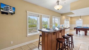 Una cocina con barra, ventanas amplias y mesa de billar.