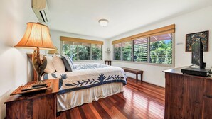 A bedroom with a bed, bedside table, lamp, and a television. - Paddle to the Beach from a Secluded Riverfront Eden-A/C-Central to Hanalei&Ke'e (Hanalei)