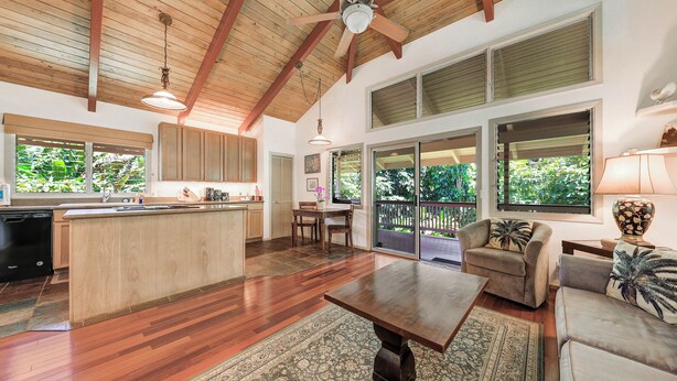 A spacious kitchen with wooden cabinets, a central island, and a dining area with a table and chairs. - Paddle to the Beach from a Secluded Riverfront Eden-A/C-Central to Hanalei&Ke'e (Hanalei)