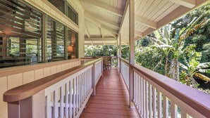 A covered outdoor area with wooden railings, a wooden floor, and a view of lush greenery. - Paddle to the Beach from a Secluded Riverfront Eden-A/C-Central to Hanalei&Ke'e (Hanalei)