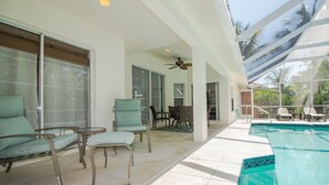 Un espacio al aire libre cubierto con piscina, sillas y ventilador de techo.
