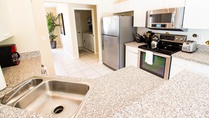 Una cocina moderna con electrodomésticos de acero inoxidable, encimeras de granito y armarios blancos.