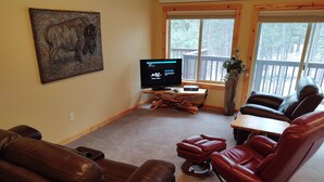 Ein Wohnzimmer mit Ledersesseln, einem Flachbildfernseher und einem Holztisch.