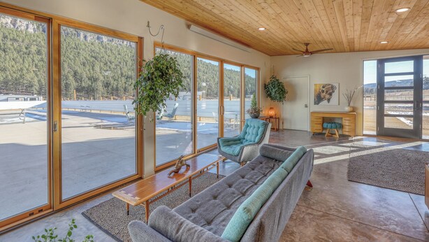 A spacious living area with a large window, a sofa, a desk, and a chair. - Private Pool Paradise - MCM Luxury Black Hills (Nemo)