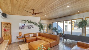 A spacious living room with a large sectional sofa, a wooden ceiling, and large windows offering a view of the outdoors. - Private Pool Paradise - MCM Luxury Black Hills (Nemo)