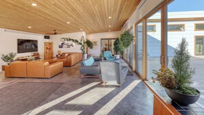 A spacious living area with a wooden ceiling, large windows, and multiple seating arrangements. - Private Pool Paradise - MCM Luxury Black Hills (Nemo)