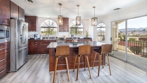 A modern kitchen with a large island, stainless steel appliances, and wooden bar stools. - Luxury Estate in Prime Location w Panoramic views of Lake Havasu (Lake Havasu City)