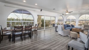 A spacious living area with a dining table and chairs, a blue sofa, and a large window offering a view of the landscape. - Luxury Estate in Prime Location w Panoramic views of Lake Havasu (Lake Havasu City)