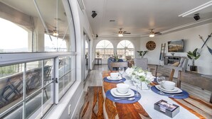 A dining area with a long table set for four, large windows, and a view of the outdoors. - Luxury Estate in Prime Location w Panoramic views of Lake Havasu (Lake Havasu City)