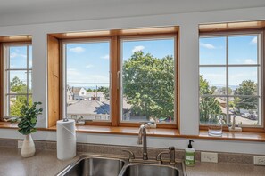 Eine Küche mit doppelter Spüle, Holzfensterrahmen und Blick auf eine Wohnstraße.