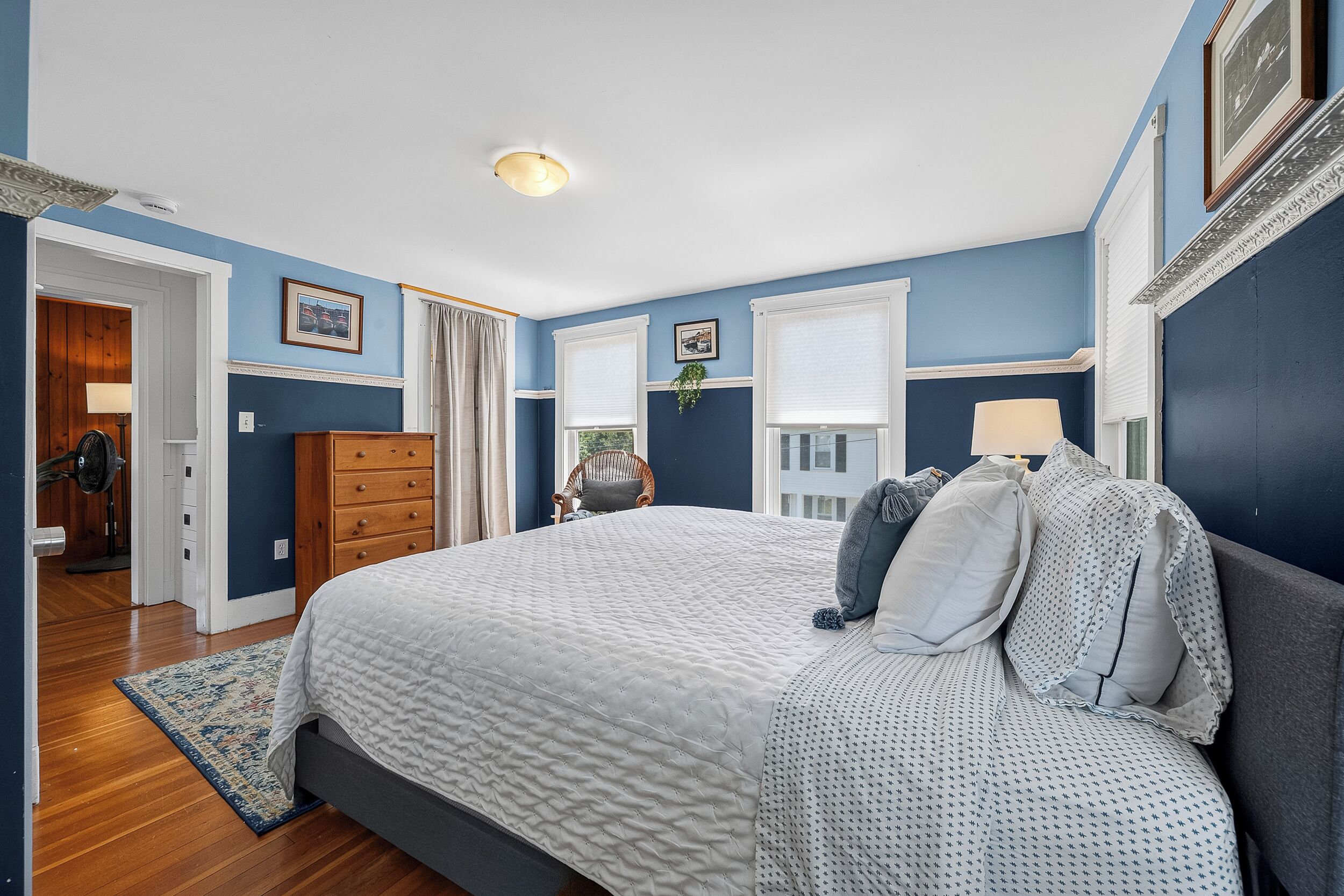 A bedroom with a large bed, a dresser, a chair, and a window.