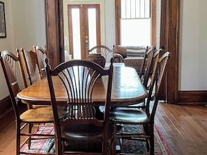 Un comedor con una mesa y sillas de madera, un tapete y un sofá al fondo.