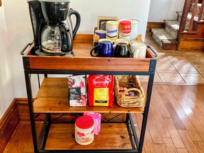 A coffee station with a coffee maker, cups, and coffee bags.