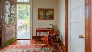 Una habitación con un escritorio de madera, una silla, un cuadro enmarcado y una alfombra estampada.