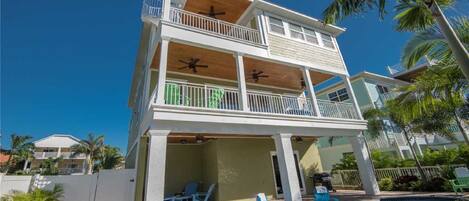 Una casa de dos pisos con piscina, balcones y mobiliario exterior.