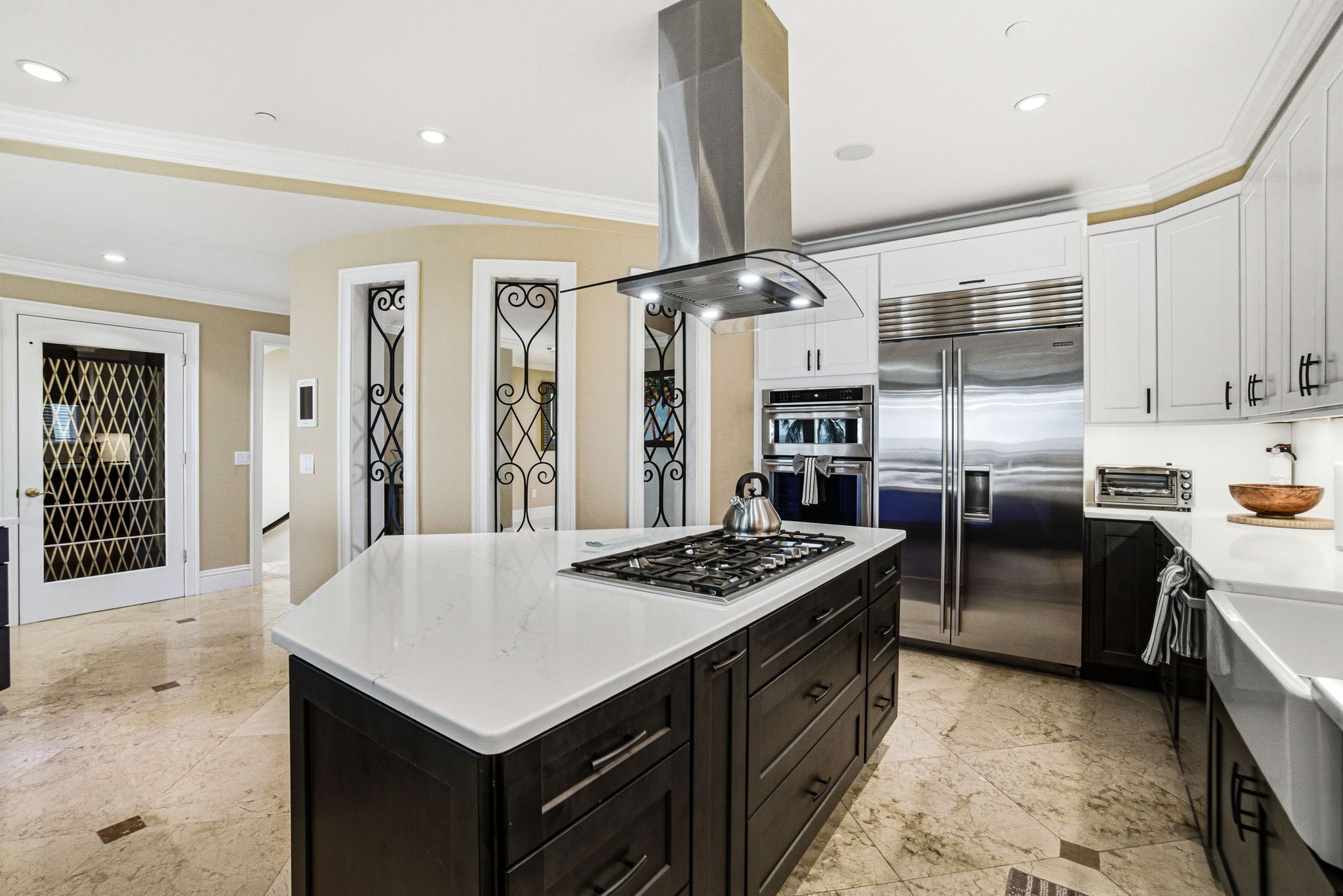 A modern kitchen with a central island, stainless steel appliances, and dark cabinetry.