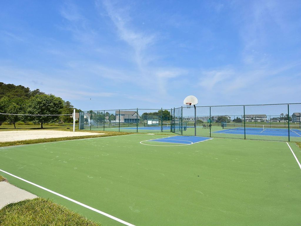 An outdoor basketball court with a net, a hoop, and a blue and green playing surface.