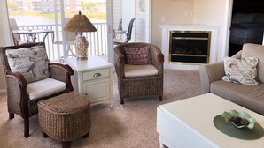 A cozy living room with wicker furniture, a fireplace, and a view of a building outside.