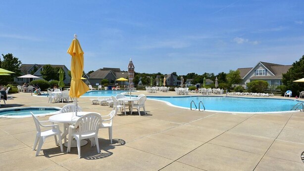 A pool area with multiple pools, white lounge chairs, and yellow umbrellas.