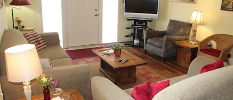 A living room with a sofa, armchair, coffee table, and a TV.