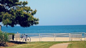 A coastal walkway with a bicycle, a wooden fence, and a bench. - Highly rated, clean, ground floor condo w/pool; steps to beach. (Virginia Beach)