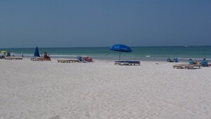 A beach with several sun loungers and umbrellas.