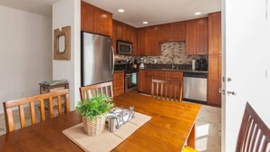 A modern kitchen with wooden cabinets, stainless steel appliances, and a dining area with a table and chairs. - Family Friendly Beach House - Rare Central Air Conditioning, Close to Town/Beach (Carlsbad)