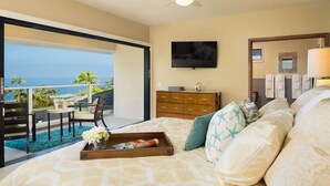 Une chambre avec un lit, une commode, une télévision et un balcon donnant sur l’océan.