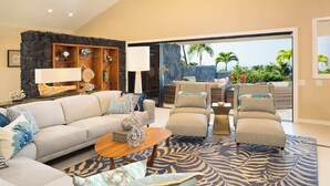 Un salon spacieux avec un grand canapé, deux fauteuils, une table basse et un tapis à motifs.