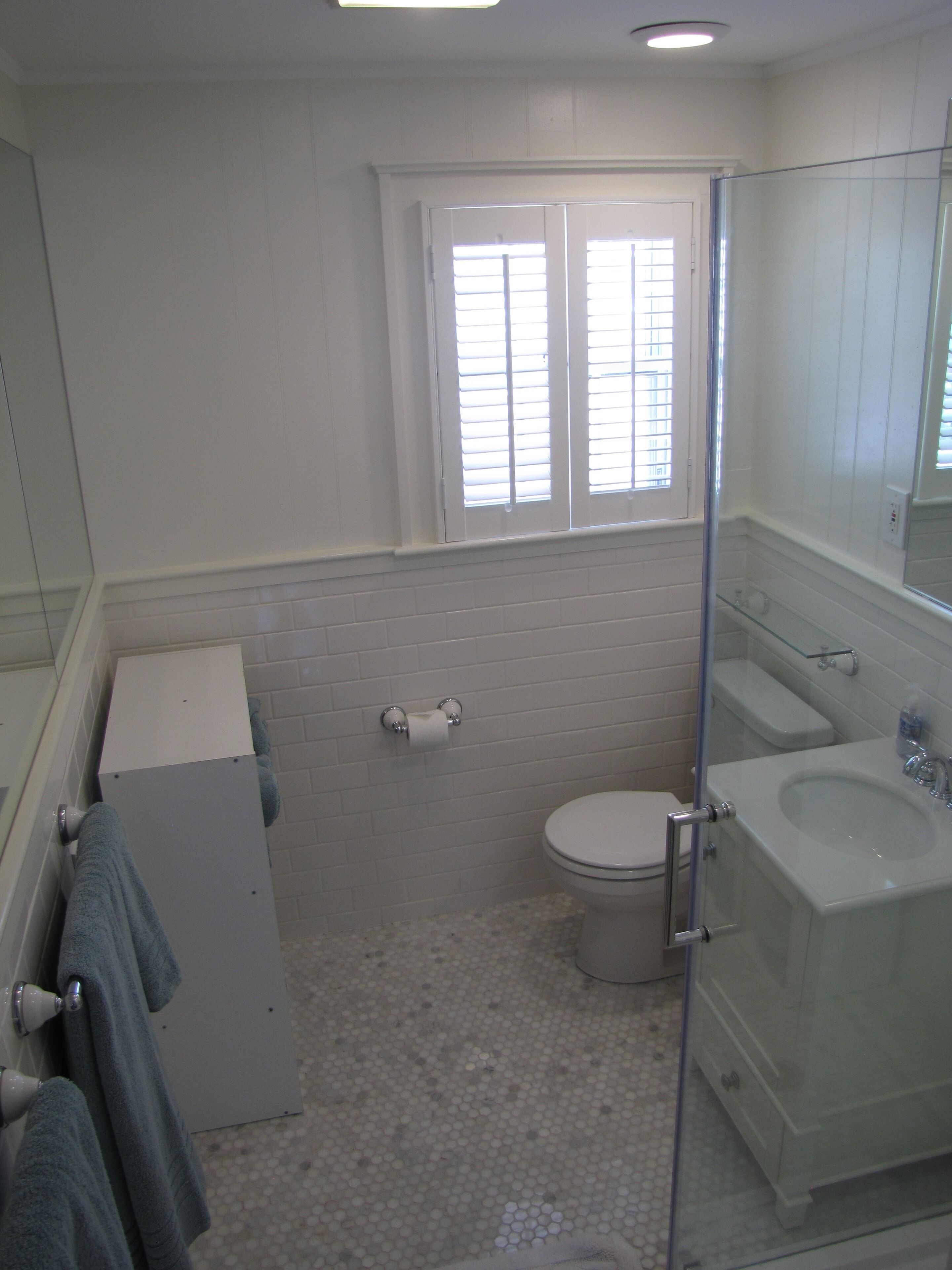 Un bagno con il water, una cabina doccia in vetro, un lavandino e uno specchio.