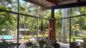 Un comedor con paredes de vidrio y vistas a una piscina y palmeras.