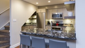 Eine moderne Küche mit Granitarbeitsplatte, Edelstahlgeräten und einem eingebauten Backofen.