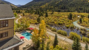 Un quartier résidentiel avec une piscine, un parasol rouge et une rivière.